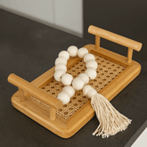 bandeja de madeira com colar decorativo em cima da bancada da sala